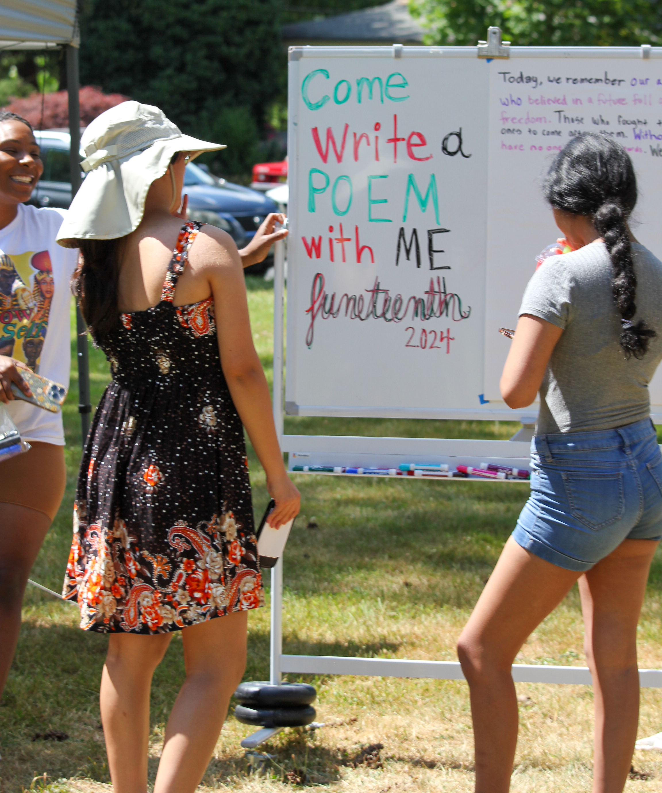 White-shirted woman, Sherrie Yvette, and community members reading collaborative Juneteenth poem